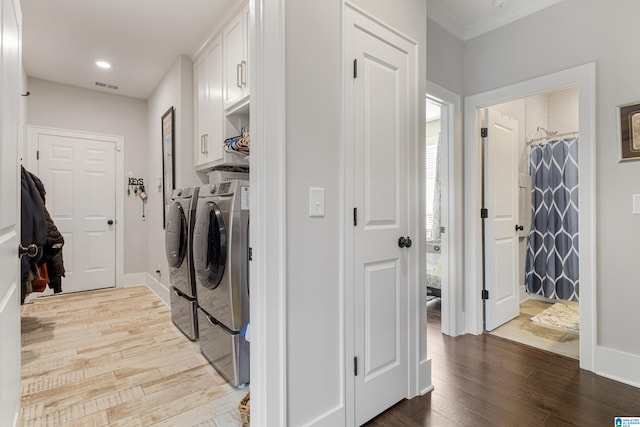 washroom with ornamental molding, cabinets, wood-type flooring, and washer and clothes dryer