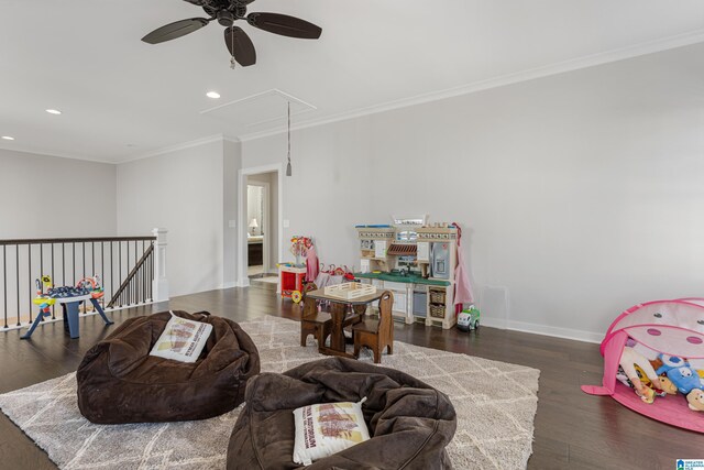 recreation room with dark wood-type flooring, ceiling fan, and ornamental molding