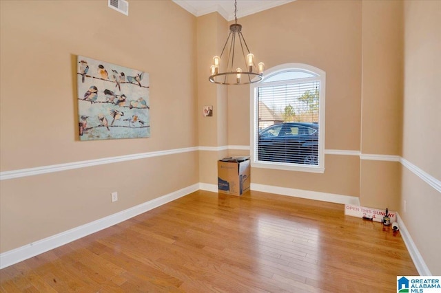 unfurnished dining area with wood-type flooring, a notable chandelier, and ornamental molding