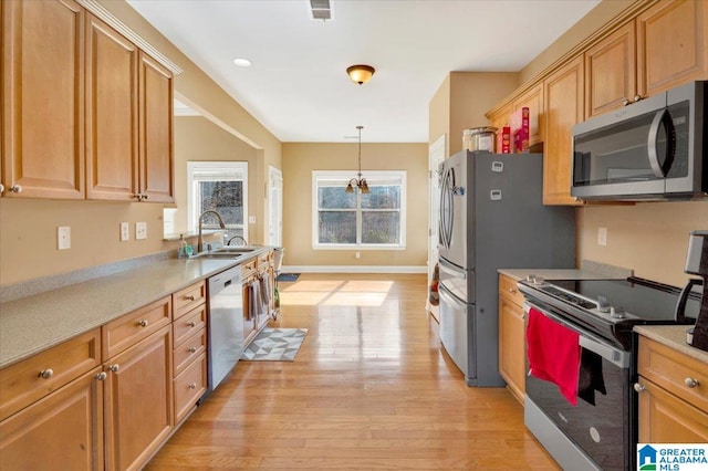 kitchen with decorative light fixtures, sink, stainless steel appliances, and light hardwood / wood-style floors