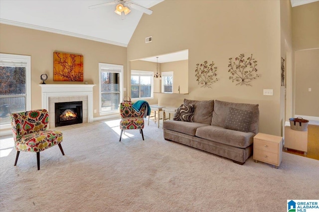 living room featuring light carpet, ceiling fan, high vaulted ceiling, crown molding, and a tiled fireplace