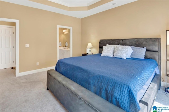 bedroom with a tray ceiling, ensuite bathroom, ornamental molding, and carpet flooring