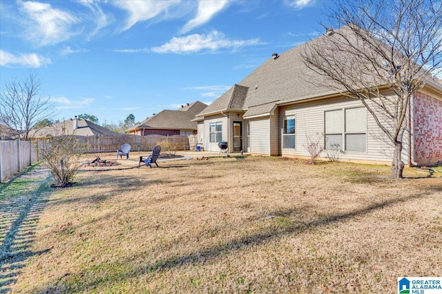 rear view of property with an outdoor fire pit and a lawn