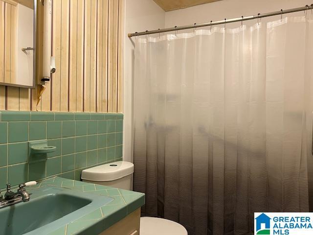 bathroom featuring vanity, toilet, and tile walls