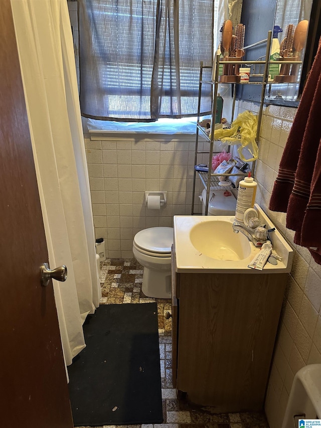 bathroom with vanity, toilet, and tile walls