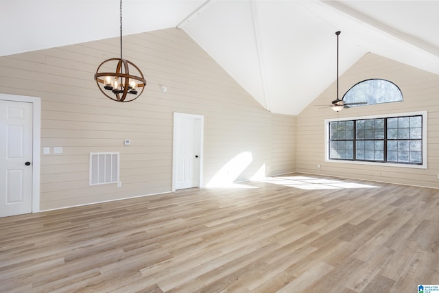 unfurnished living room featuring ceiling fan with notable chandelier, light hardwood / wood-style floors, high vaulted ceiling, and wood walls