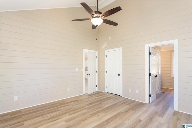 spare room featuring wooden walls, light hardwood / wood-style flooring, and ceiling fan