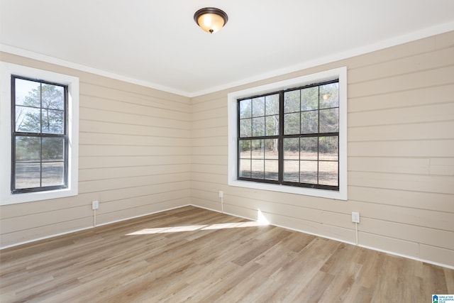 unfurnished room featuring light hardwood / wood-style floors, a wealth of natural light, and ornamental molding