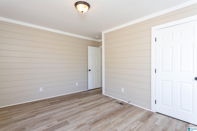 unfurnished bedroom featuring wood walls and light hardwood / wood-style floors