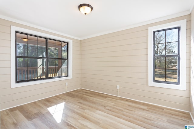 unfurnished room featuring wood walls, light hardwood / wood-style flooring, and ornamental molding