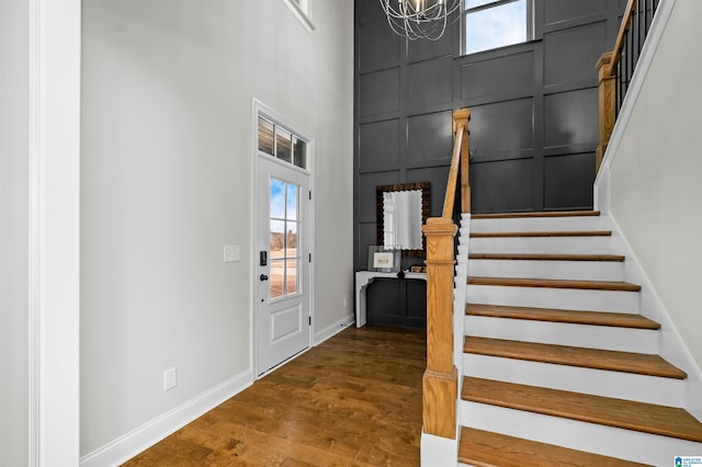 entryway with a high ceiling, an inviting chandelier, and dark wood-type flooring