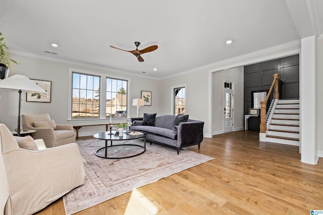 living room with hardwood / wood-style flooring, ceiling fan, and ornamental molding