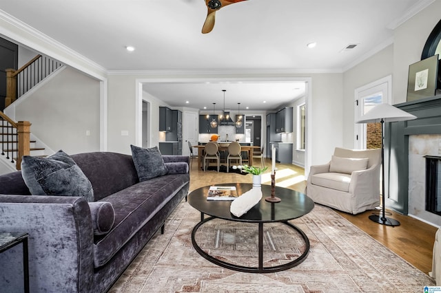 living room featuring crown molding, ceiling fan, and light hardwood / wood-style floors