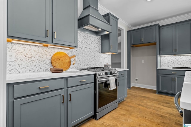 kitchen featuring gray cabinetry, light hardwood / wood-style flooring, ornamental molding, custom range hood, and stainless steel range with gas stovetop