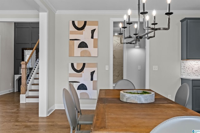 dining area with sink, dark wood-type flooring, a chandelier, and ornamental molding