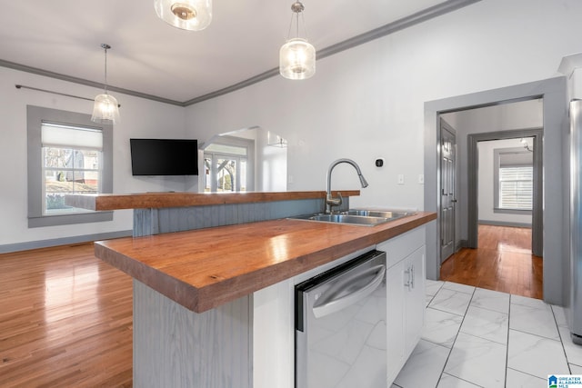 kitchen with sink, pendant lighting, stainless steel dishwasher, wooden counters, and a kitchen island with sink