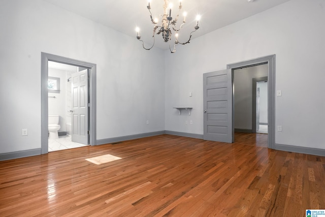 empty room with light hardwood / wood-style flooring and a chandelier