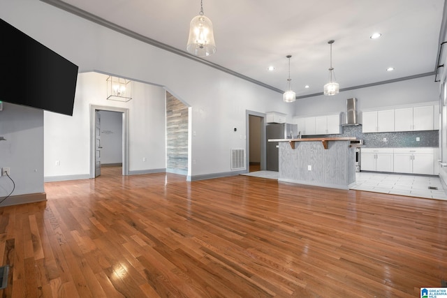 unfurnished living room featuring light wood-type flooring and crown molding