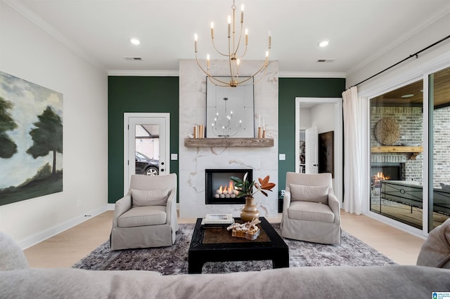 living room featuring hardwood / wood-style flooring, crown molding, a fireplace, and an inviting chandelier