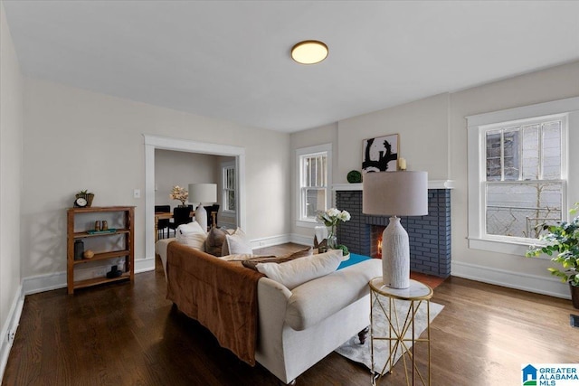 living room featuring a brick fireplace and dark wood-type flooring