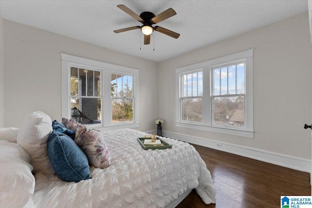 bedroom with ceiling fan, dark wood-type flooring, multiple windows, and a textured ceiling