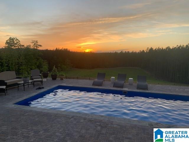 pool at dusk featuring a patio