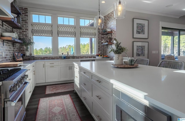 kitchen featuring ornamental molding, pendant lighting, dark wood-type flooring, high end stove, and white cabinetry