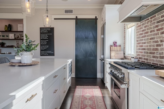 kitchen featuring a barn door, custom range hood, high quality appliances, pendant lighting, and white cabinetry