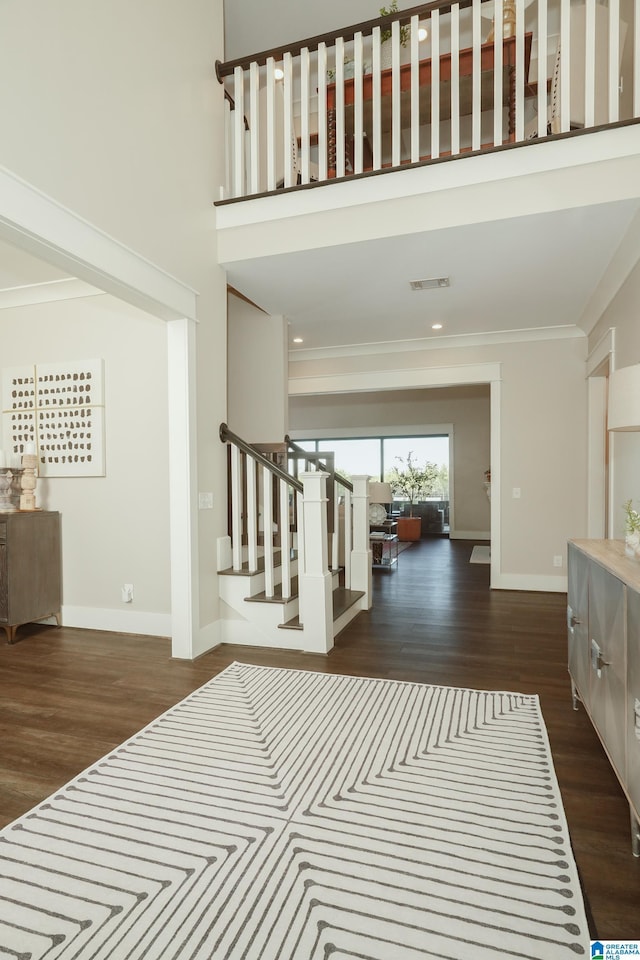 interior space with a towering ceiling, crown molding, and wood-type flooring