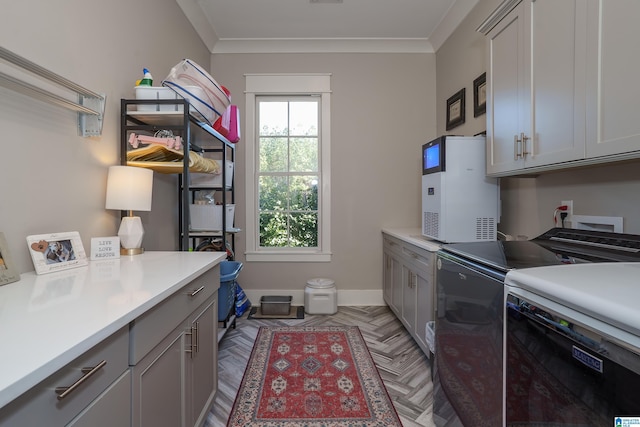 laundry room with washer and dryer, cabinets, ornamental molding, and light parquet flooring