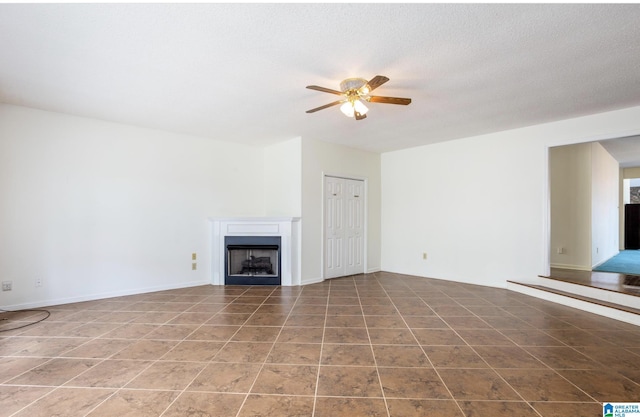 unfurnished living room with tile patterned floors, ceiling fan, and a textured ceiling