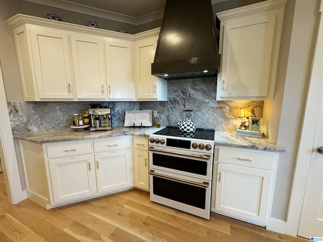 kitchen featuring double oven range, white cabinetry, decorative backsplash, light wood-type flooring, and custom range hood