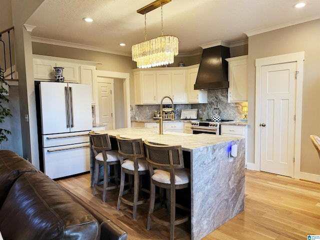 kitchen featuring custom exhaust hood, white cabinetry, electric stove, hanging light fixtures, and high end fridge