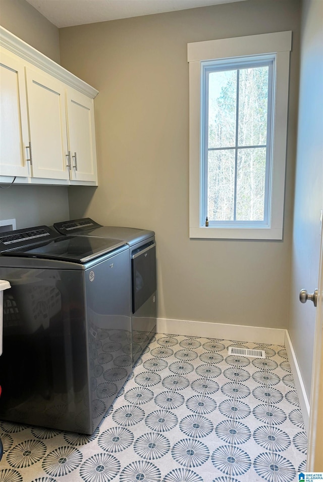 laundry area featuring light tile patterned flooring, washing machine and clothes dryer, and cabinets