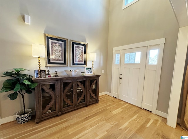 entrance foyer featuring light wood-type flooring, a towering ceiling, and a wealth of natural light