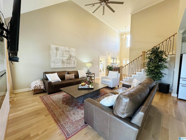 living room featuring ceiling fan with notable chandelier, light hardwood / wood-style flooring, and high vaulted ceiling