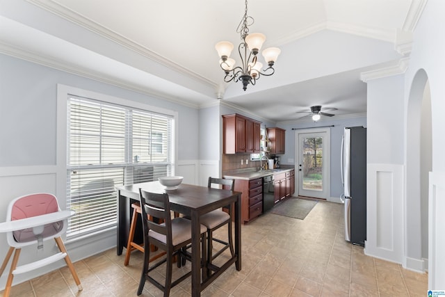 tiled dining space with crown molding, plenty of natural light, ceiling fan with notable chandelier, and vaulted ceiling