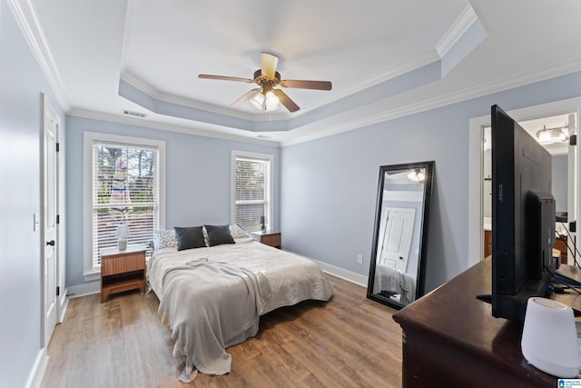 bedroom with ceiling fan, hardwood / wood-style floors, a tray ceiling, and crown molding