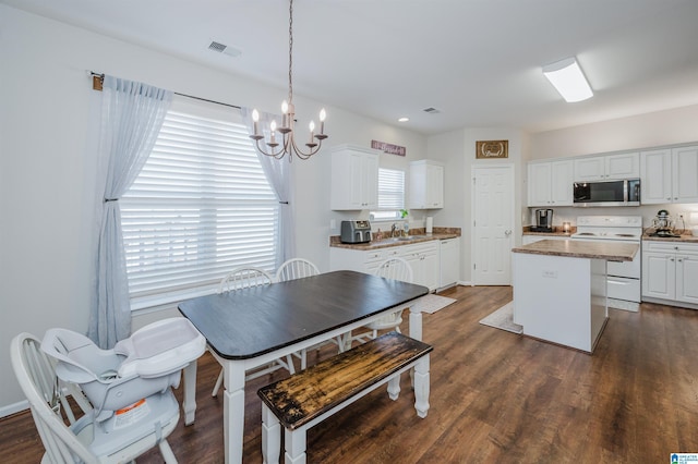 dining space with a healthy amount of sunlight, dark wood-type flooring, and an inviting chandelier