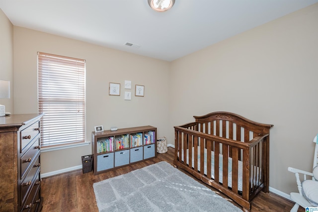 bedroom featuring a crib and dark wood-type flooring