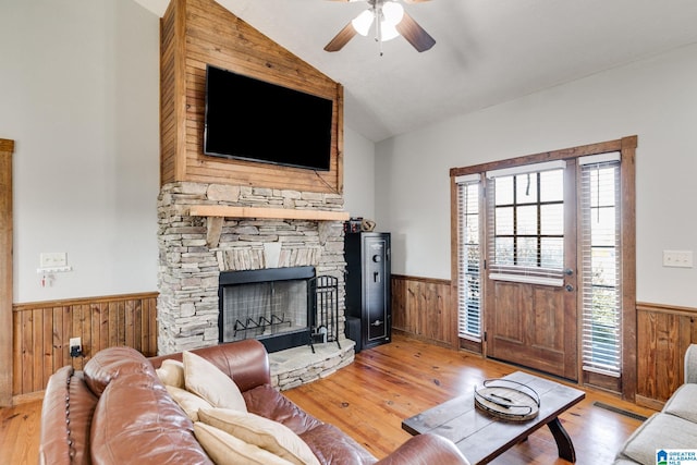 living room with ceiling fan, a fireplace, light hardwood / wood-style floors, and vaulted ceiling