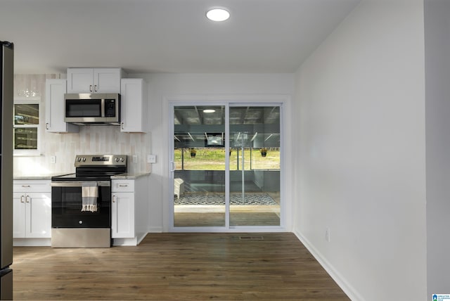 kitchen with white cabinets, light stone counters, appliances with stainless steel finishes, tasteful backsplash, and dark hardwood / wood-style flooring