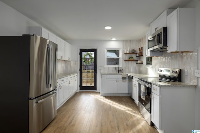 kitchen with white cabinets, sink, decorative backsplash, light hardwood / wood-style floors, and stainless steel appliances