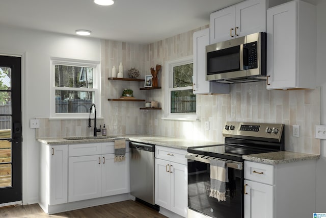 kitchen with decorative backsplash, white cabinetry, sink, and appliances with stainless steel finishes