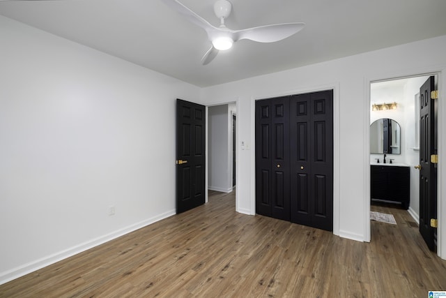 unfurnished bedroom featuring a closet, connected bathroom, hardwood / wood-style flooring, and ceiling fan