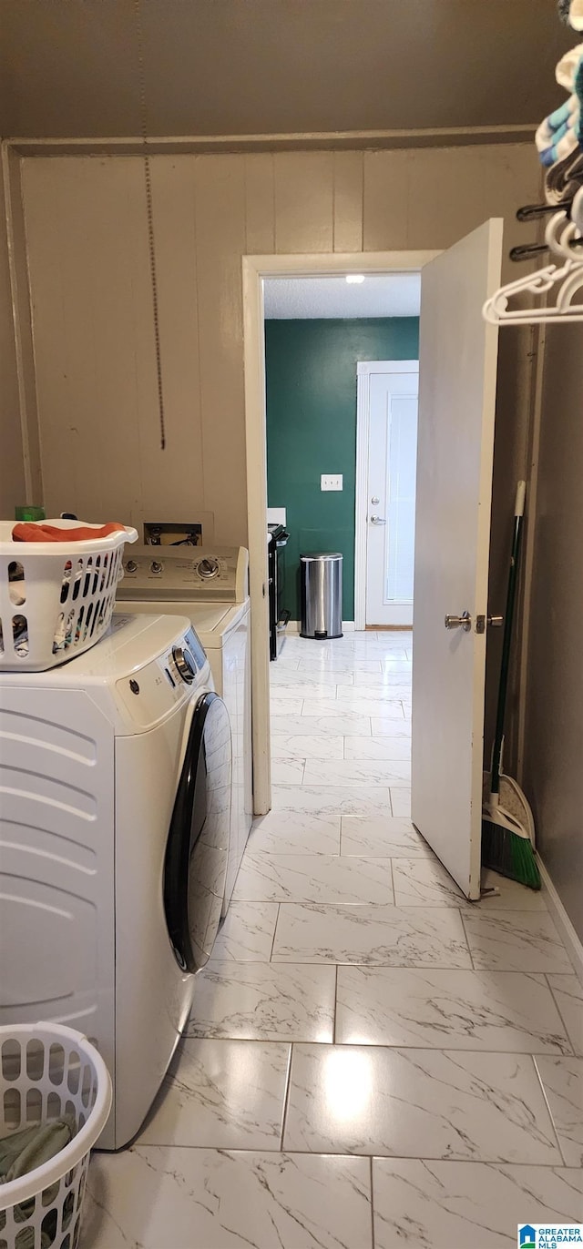 laundry room featuring separate washer and dryer and wooden walls