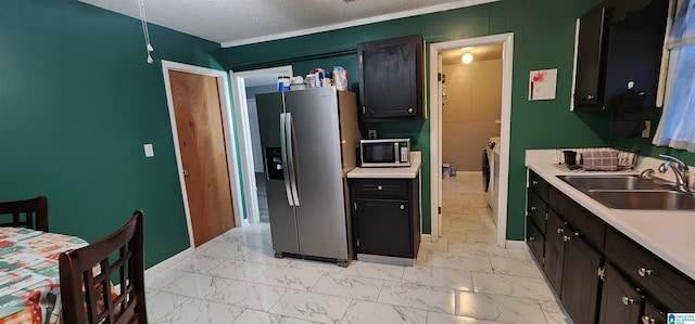 kitchen featuring washer and clothes dryer, sink, a textured ceiling, and appliances with stainless steel finishes