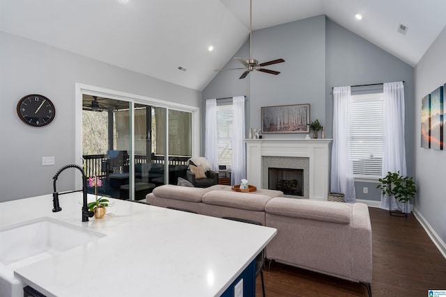 living room featuring dark hardwood / wood-style flooring, ceiling fan, sink, and high vaulted ceiling