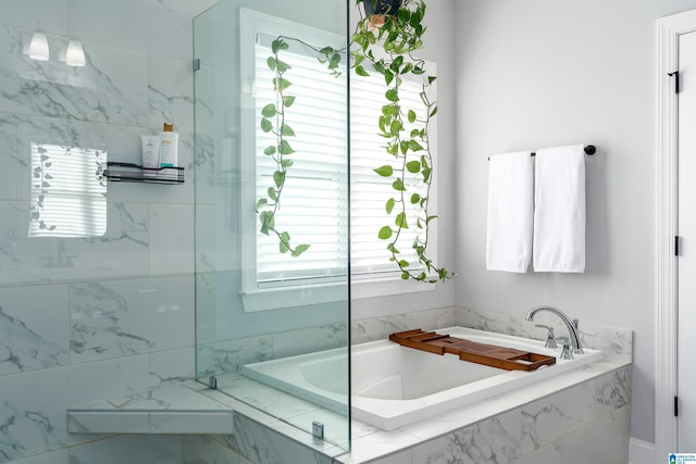 bathroom featuring tiled bath and a wealth of natural light