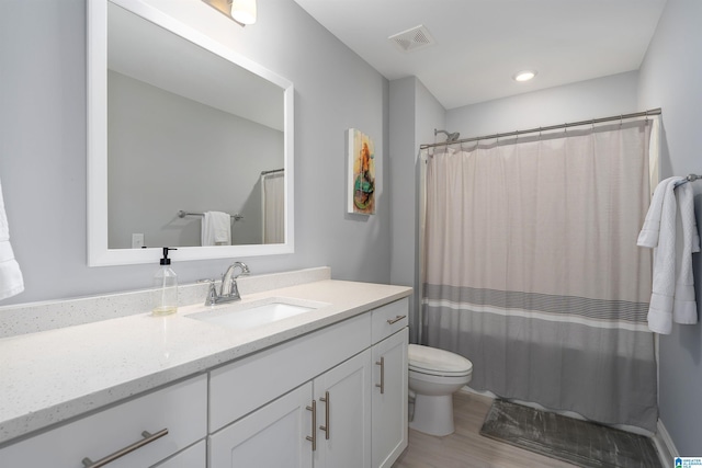 bathroom with wood-type flooring, vanity, toilet, and curtained shower